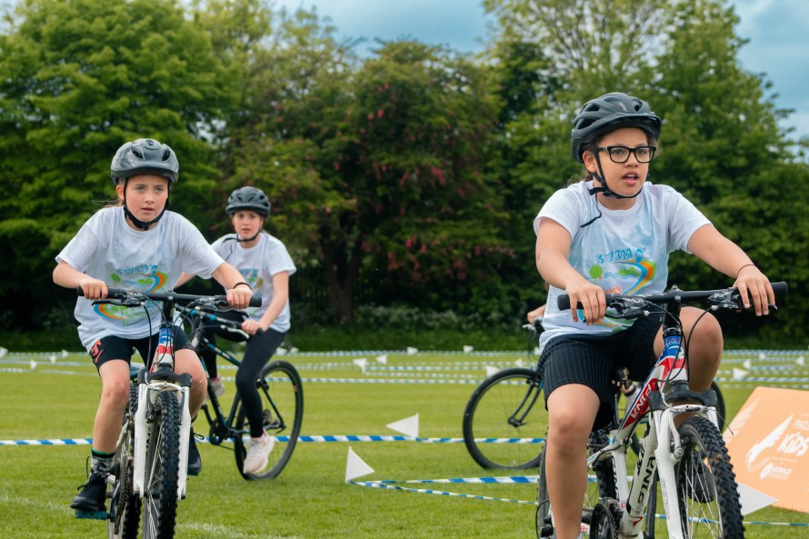 Three young girls riding bicycles as a part of the Brownlee Triathlon.