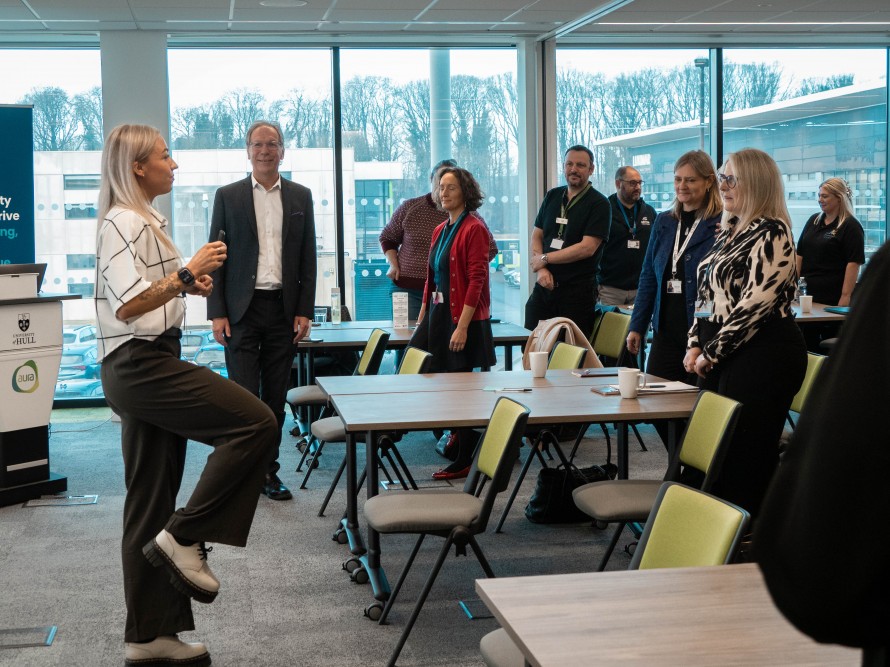 A room of people in formal clothes doing a stretch session at a conference