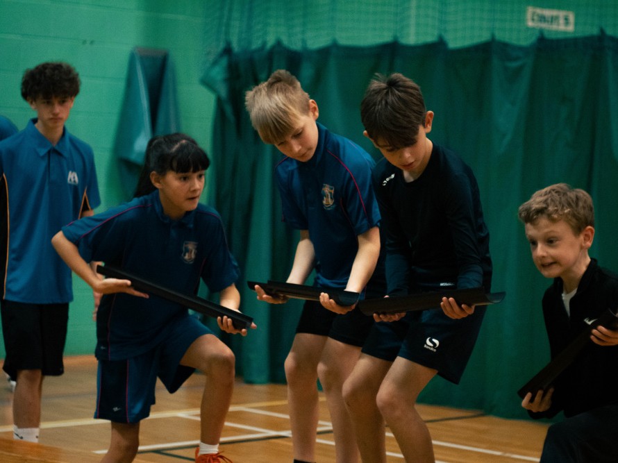 Four children holding pieces of guttering to allow a ball roll down it as part of a team building exercise
